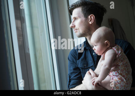 Vater Blick durch Fenster mit Tochter (2-5 Monate) Stockfoto