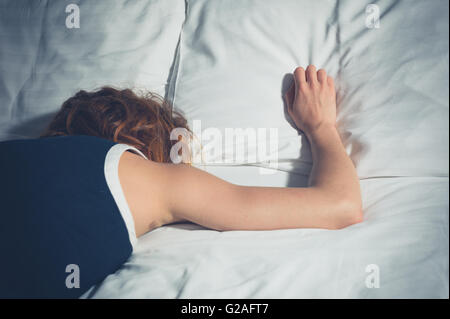 Eine junge Frau trägt eine Kleid auf einem Bett ohnmächtig Stockfoto