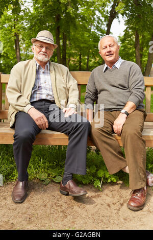 Zwei alte Männer sitzen auf einer Parkbank im Sommer Stockfoto