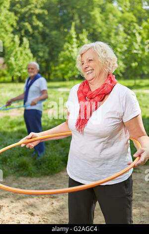 Zwei glückliche ältere Leute, die Sport mit dem Reifen in der Natur Stockfoto