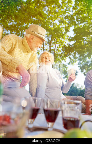 Glückliche Gruppe von Senioren Spielkarten im Sommer in einem park Stockfoto