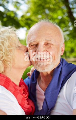 Glückliche Frau küssen Greis auf die Wange im Sommergarten Stockfoto