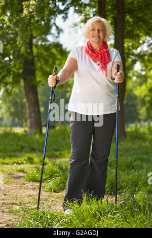 Ältere lächelnde Frau tun, Nordic-walking in einem Wald im Sommer Stockfoto