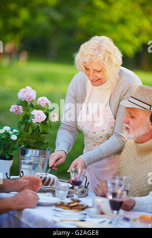 Ältere Frau Guglhupf auf Geburtstagsparty in einem Garten Stockfoto