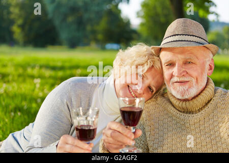 Gerne älteres paar trinken Rotwein in einem Garten im Herbst Stockfoto