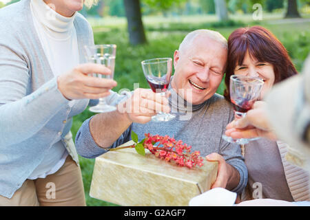 Alte Freunde auf Geburtstagsparty jubeln mit Glas Rotwein Stockfoto