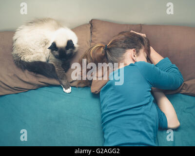 Eine junge Frau schläft in einem Bett mit einer Katze neben ihr Stockfoto