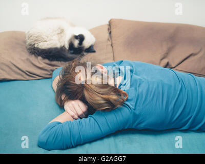 Eine junge Frau schläft in einem Bett mit einer Katze neben ihr Stockfoto