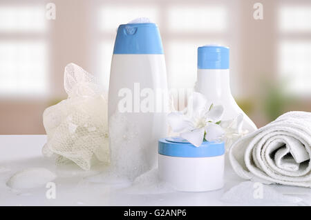 Körper-Pflege und Beauty-Produkte in weißen und blauen Container auf einem weißen Tisch Glas in ein Bad mit Schaum. Ansicht von vorne. Stockfoto
