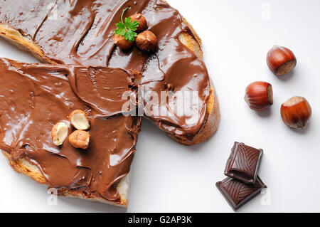 Zwei Scheiben Brot mit Schokoladencreme und Haselnüssen weiße isoliert Draufsicht. Haselnuss und Schokolade Dekoration. Stockfoto