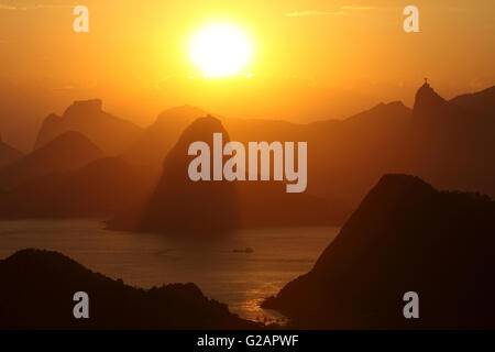 Übersicht über die Berge von Rio De Janeiro und Eingang der Guanabara-Bucht bei Sonnenuntergang mit Zuckerhut in der Mitte, Pedra da Gavea (Rock Gavea) auf der linken Seite - Hintergrund und Corcovado Berg mit Christus der Erlöser Statue auf davon auf der rechten Seite, Brasilien. Stockfoto