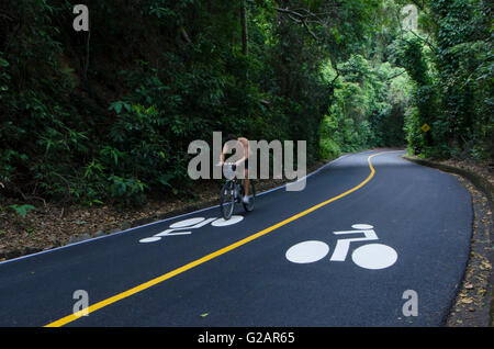 Radfahrer fährt im Tijuca Wald (Floresta da Tijuca in portugiesischer Sprache), eines bergigen Hand gepflanzt Regenwaldes in der Stadt Rio De Janeiro, Brasilien - es ist ein UNESCO-Weltkulturerbe und der weltweit größten Stadtwald, über einige 32 km ² (12,4 mi²) - der Tijuca Wald ist Heimat für Hunderte von Arten von Flora und Fauna, viele vom Aussterben bedroht, und fand nur im Atlantischen Regenwald (Mata Atlantica in portugiesischer Sprache). Die Vegetation ist so dicht, dass Wissenschaftler haben schätzungsweise Umgebungstemperaturen in der Umgebung von bis zu 9 ° c gesenkt haben Stockfoto