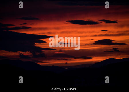 Sonnenuntergang über dem Egaleo Gebirge Athen Griechenland // ATHEN, Griechenland – Ein dramatischer roter Sonnenuntergang beleuchtet die westliche Skyline von Athen. Die Sonne untergeht hinter dem Egaleo-Gebirge, das die westliche Grenze der Stadt bildet und eine Höhe von 468 Metern (1.535 Fuß) erreicht. Die Silhouetten von Gebäuden im westlichen Athen und möglicherweise Teilen von Piräus, die etwa 12 km (7,5 Meilen) südwestlich von Zentral-Athen liegen, sind vor dem lebendigen Himmel sichtbar. Diese Szene, die in Athen aufgrund des mediterranen Klimas häufig ist, wird durch die atmosphärischen Bedingungen und die Höhe der Stadt von 70-300 Metern (230-984 fe Stockfoto