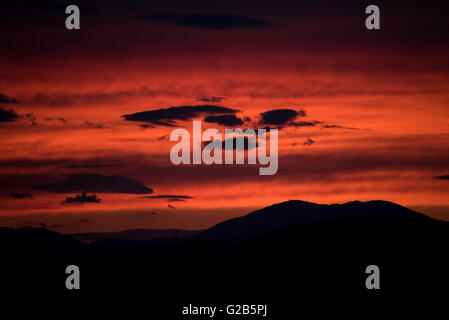 Roter Sonnenuntergang über dem Egaleo-Berg Athen Griechenland // ATHEN, Griechenland – Ein dramatischer roter Sonnenuntergang beleuchtet die westliche Skyline von Athen. Die Sonne untergeht hinter dem Egaleo-Gebirge, das die westliche Grenze der Stadt bildet und eine Höhe von 468 Metern (1.535 Fuß) erreicht. Die Silhouetten von Gebäuden im westlichen Athen und möglicherweise Teilen von Piräus, die etwa 12 km (7,5 Meilen) südwestlich von Zentral-Athen liegen, sind vor dem lebendigen Himmel sichtbar. Diese Szene, die in Athen aufgrund seines mediterranen Klimas häufig ist, wird durch die atmosphärischen Bedingungen und die Höhe der Stadt von 70-300 Metern (230-984 Fuß) intensiviert Stockfoto