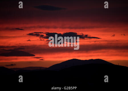 Sonnenuntergang über dem Egaleo Gebirge Athen Griechenland // ATHEN, Griechenland – Ein dramatischer roter Sonnenuntergang beleuchtet die westliche Skyline von Athen. Die Sonne untergeht hinter dem Egaleo-Gebirge, das die westliche Grenze der Stadt bildet und eine Höhe von 468 Metern (1.535 Fuß) erreicht. Die Silhouetten von Gebäuden im westlichen Athen und möglicherweise Teilen von Piräus, die etwa 12 km (7,5 Meilen) südwestlich von Zentral-Athen liegen, sind vor dem lebendigen Himmel sichtbar. Diese Szene, die in Athen aufgrund des mediterranen Klimas häufig ist, wird durch die atmosphärischen Bedingungen und die Höhe der Stadt von 70-300 Metern (230-984 fe Stockfoto