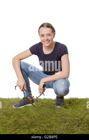 glückliche Frau bereit, einige Gartenarbeit hält eine Kelle und Gabel gedreht im Studio mit Rasen zu tun Stockfoto