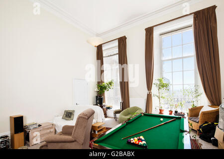 Cavendish Place, Brighton. Überfüllten Wohnbereich mit Billard-Tisch und Stühlen. Große Fenster mit zurückgezogen Vorhänge. Stockfoto