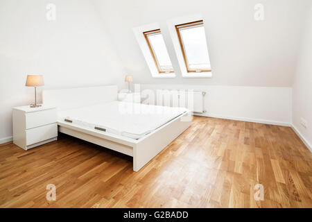 Umwandlung von Dach oder Dachboden in der Reichenberger Straße in Kreuzberg. Moderne Schlafzimmer mit schrägen Wänden. Weiße Wände und Holzböden mit minimalen Möbeln und Dekoration. Stockfoto