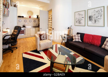 Foley House, Maddox Street. Offene Wohn- und Essbereich mit kleiner Küche am Ende des Raumes. Zeitgenössische Möbel und Dekorationen. Union Jack Bereich Teppich. Stockfoto