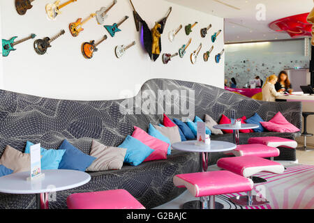 Nhow Hotel eröffnet im Jahr 2010 als Musik und Lifestyle Hotel an der Spree in Berlin. Teilansicht des Café-Bereich. Bank und rosa Hocker. Gitarren, die entlang der Wand. Zwei Frauen im Hintergrund an einem erhöhten Tisch sitzen. Stockfoto