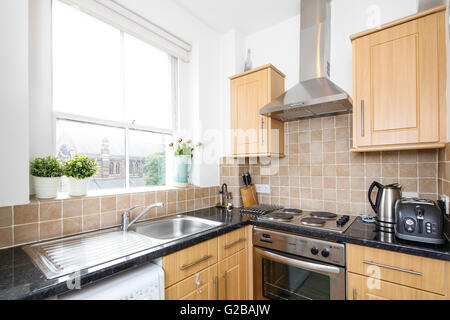 Park House, Harrington Road. Moderne Küche mit frischem Holz Schränke und schwarze Arbeitsplatten. Großes Fenster über Waschbecken. Stockfoto