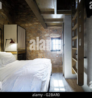 Tenaro blau Retreat in Mani, Griechenland. Blick aus einem Schlafzimmer mit Steinmauern und eine Leiter an der Wand hängen. Bett mit weißem Leinen. Stockfoto