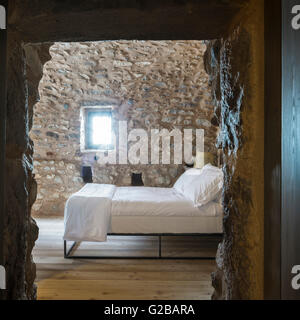 Tenaro blau Retreat in Mani, Griechenland. Blick aus einem Schlafzimmer durch die Tür. Bett mit weißem Leinen. Stein-Wand mit einem Fenster. Stockfoto