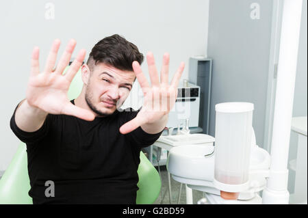 Gut aussehend männlichen Patienten handeln Angst in Zahnarztpraxis wie Angst vor dem Zahnarzt-Konzept Stockfoto