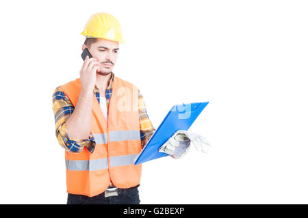 Junge Konstruktor mit einem Klemmbrett während des Gesprächs auf Smartphone isoliert auf weißem Hintergrund Stockfoto