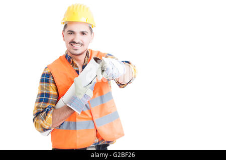 Attraktives Lächeln Ingenieur mit Helm Zeigefinger auf Sie halten Blaupause isoliert auf weißem Hintergrund mit copyspa Stockfoto