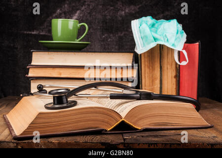 Stethoskop auf offenes Buch und Kaffee auf Stapel Bücher Stockfoto