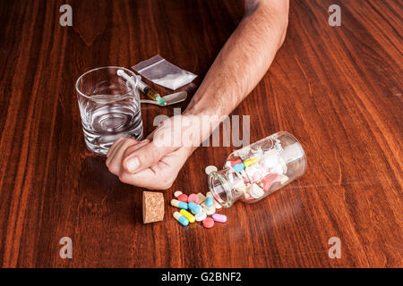 Pillen und Medikamente mit leeren Glas und Hand auf braunen Holz Tisch Stockfoto