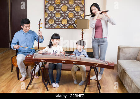 Junge Familie, die traditionellen Musikinstrumente zu Hause spielen Stockfoto