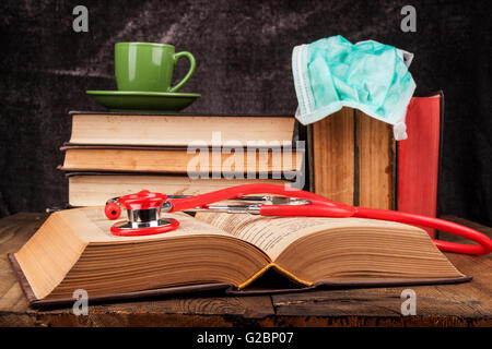 Stethoskop auf offenes Buch und Kaffee auf Stapel Bücher Stockfoto