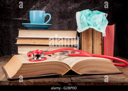 Stethoskop auf offenes Buch und Kaffee auf Stapel Bücher Stockfoto