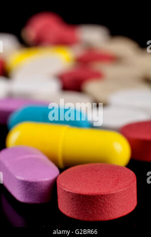 Farbigen Pillen Medizin auf schwarzem Hintergrund mit Reflexion Stockfoto
