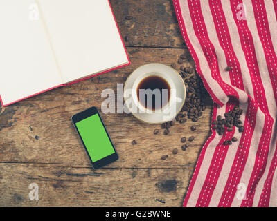 Overhead Schuss von Kaffee-Konzept mit Tasse, Geschirrtuch, ein offenes Buch und ein Smartphone mit einem green-screen Stockfoto