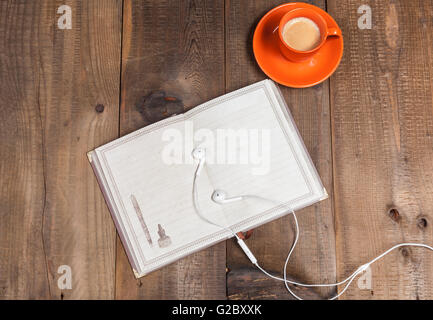Kopfhörer auf leeren Notebook mit Kaffee auf Holztisch Stockfoto