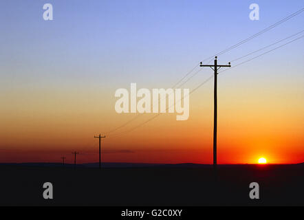 TELEFON & STROMLEITUNGEN BEI SONNENUNTERGANG; IN DER NÄHE VON SHIPROCK; NEW MEXIKO; USA Stockfoto