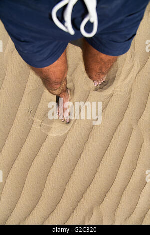 Beine von einem Mann zu Fuß und Fuß verlassen zu drucken, auf dem sand Stockfoto