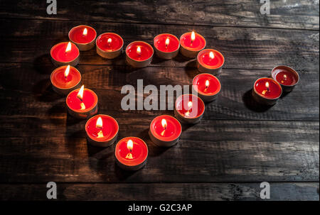 glühende kleine rote Kerzen in Herzform auf Holztisch angeordnet. Draufsicht mit Textfreiraum. Stockfoto