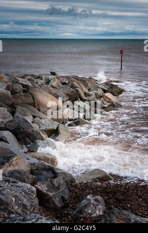 Wellenbrecher an Großbritanniens Jurassic Südküste zeigt abwechslungsreiche Rock Farben und braunen Meer. Stockfoto