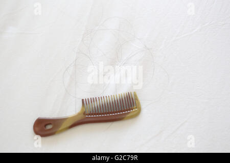 Kamm und Schwarzes Haar der Frauen platziert auf dem weißen Tuch in das Konzept Problem des Haarausfalls. Stockfoto