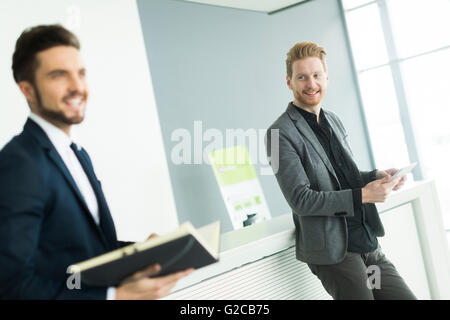 Zwei junge Männer mit Tablet und Datei im modernen Büro Stockfoto