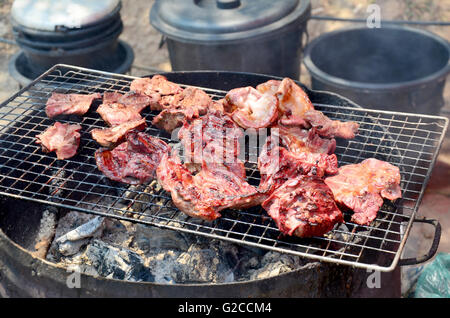 Laotische Menschen kochen Schweinefleisch gebraten und Innereien vom Schwein gegrillt für den Verkauf auf dem alten Herd im lokalen Markt in Luang Prabang, Laos Stockfoto