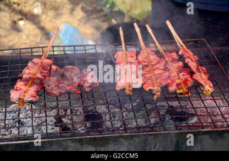 Laotische Menschen kochen Schweinefleisch gebraten und Innereien vom Schwein gegrillt für den Verkauf auf dem alten Herd im lokalen Markt in Luang Prabang, Laos Stockfoto