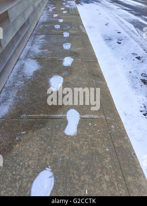 Winterbild bestehend aus gefrorenen Spuren auf einem kalten Beton Gehsteig Stockfoto