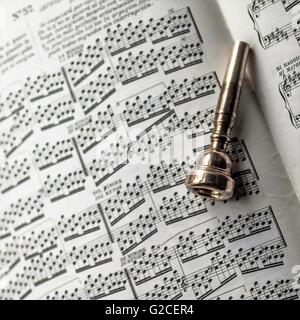 Trompete Mundstück posierten auf ein Buch von Notenblätter Stockfoto