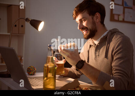 Mann mit Laptop und Pizza essen Stockfoto