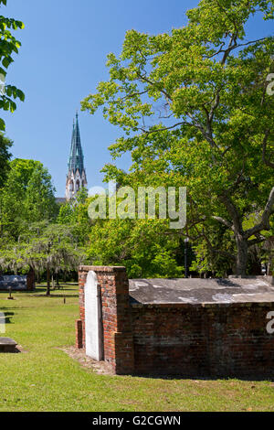 Savannah, Georgia - Colonial Park Cemetery, mit der Kathedrale St. Johannes des Täufers im Hintergrund. Stockfoto